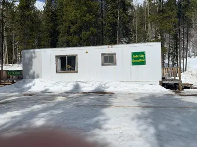 a white building with a sign on it in the snow at Jade City Bungalow in Jade City