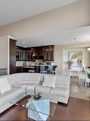 a living room with a white couch and a kitchen at Seaview Executive Home in Ladysmith
