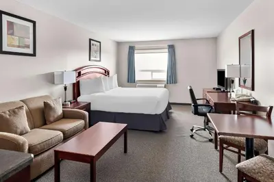 a hotel room with a bed and a living room at SureStay Plus Hotel by Best Western Hardisty in Hardisty