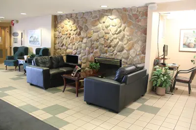 a waiting room with couches and a stone wall at Travelodge by Wyndham Lacombe in Lacombe