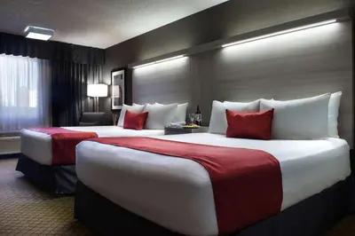 two beds in a hotel room with red and white pillows at Best Western Plus Village Park Inn in Calgary