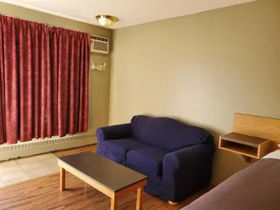 a living room with a blue chair and a table at Stars Inn - Motel in Fort Saskatchewan