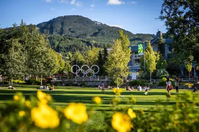 a park with people sitting in the grass with the olympic rings at 1BR in Lake Placid Lodge, Steps to Creekside Gondola, Shared Pool and Hot Tub, Lounge Access in Whistler
