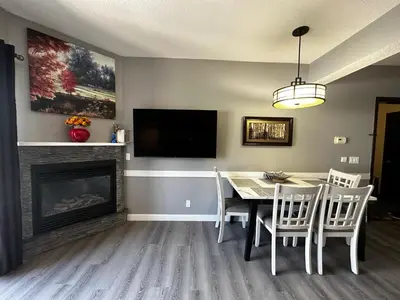 a dining room with a table and a fireplace at Luxury Two Queen Beds Condo - Grande Rockies Resort Indoor Parking Pool Hot tub GYM in Canmore