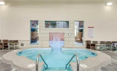 a large hot tub in a room with chairs at Luxury Two Queen Beds Condo - Grande Rockies Resort Indoor Parking Pool Hot tub GYM in Canmore