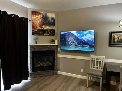 a living room with a tv on a wall with a fireplace at Luxury Two Queen Beds Condo - Grande Rockies Resort Indoor Parking Pool Hot tub GYM in Canmore
