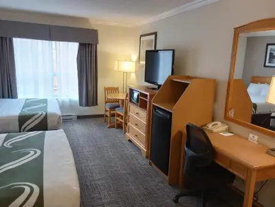 a hotel room with a bed and a desk with a computer at Quality Inn Downtown Inner Harbour in Victoria