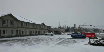 a snow covered street with cars parked in front of buildings at Westlake Inn in Strathmore