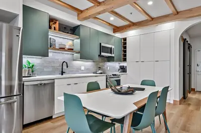 a kitchen with a white table and blue chairs at Ravens Crest Lodge - Stunning Views Perfectly Located on Main Street in Canmore