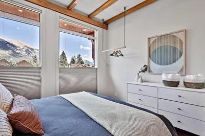 a bedroom with a bed and a window at Ravens Crest Lodge - Stunning Views Perfectly Located on Main Street in Canmore