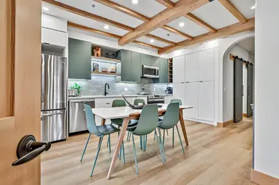 a kitchen with white cabinets and a table and chairs at Ravens Crest Lodge - Stunning Views Perfectly Located on Main Street in Canmore