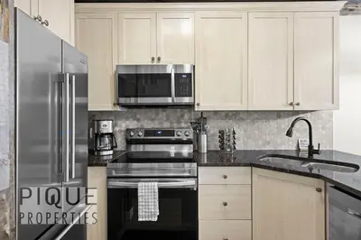 a kitchen with stainless steel appliances and white cabinets at Mystic Mountain Chalet, Heated Outdoor Pool & Hot Tub, Free Parking, Fast Wifi! in Canmore