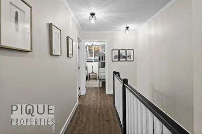 a hallway with white walls and a staircase with pictures on the wall at Mystic Mountain Chalet, Heated Outdoor Pool & Hot Tub, Free Parking, Fast Wifi! in Canmore