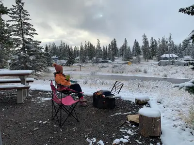 a person sitting in a chair in front of a fire at Mountain View One Bedroom Vacation Suite - WindTower 119 in Canmore