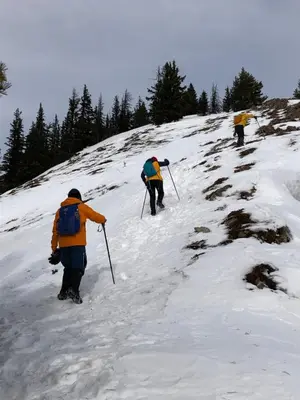 a group of people walking up a snow covered hill at Mountain View One Bedroom Vacation Suite - WindTower 119 in Canmore