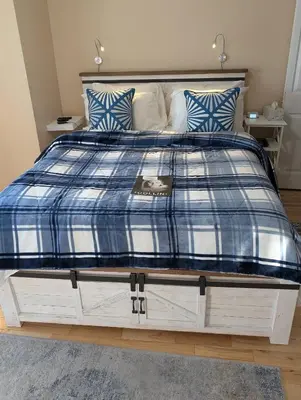 a bed with a blue and white blanket on it at Salish B&B and Spa in West Kelowna
