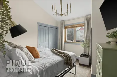 a bedroom with a bed and a chandelier at Alpine Loft with Pool, Hot Tub & Mountain Views in Canmore