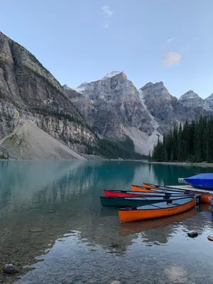 a group of boats sitting on a lake with mountains at Skyline Getaway - Mountain Views - Pool - Hot Tub in Canmore
