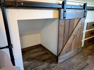a sliding barn door in a room with a wooden floor at 4 Mile Creek Cabin (Creekside) in Nelson