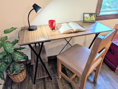 a desk with a book and a lamp and a chair at 4 Mile Creek Cabin (Creekside) in Nelson