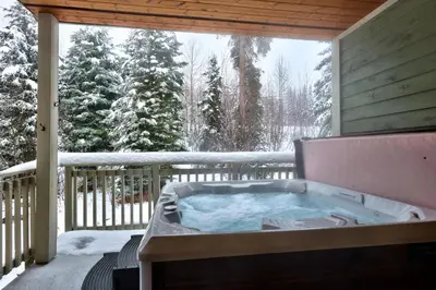 a jacuzzi tub on a porch in the snow at Settlers Crossing #29 By Bear Country in Sun Peaks