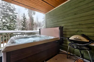 a hot tub on a deck with a grill at Settlers Crossing #29 By Bear Country in Sun Peaks