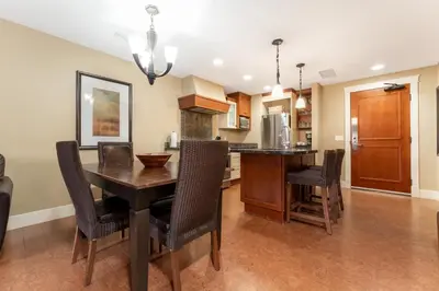 a kitchen and dining room with a wooden table and chairs at Solara Suite with Indoor Pool - Hot tub -Parking - GYM in Canmore