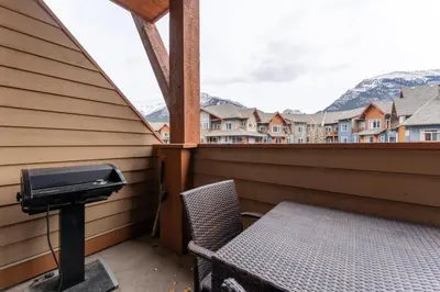 a balcony with a grill and a table and a chair at Solara Suite with Indoor Pool - Hot tub -Parking - GYM in Canmore