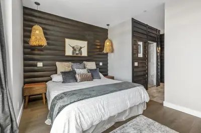 a bedroom with a large bed and a wooden wall at Chalet Monashee - Brand New High-End Property with Amazing Views in Big White