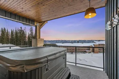 a patio with a bar and a view of the snow at Chalet Monashee - Brand New High-End Property with Amazing Views in Big White