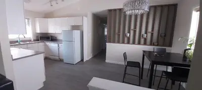 a kitchen with a table and a white refrigerator at Private Rooms in a 3 Bedroom Guest House Close to Londonderry Mall 1 Person per Room No Couples For Men Only in Edmonton