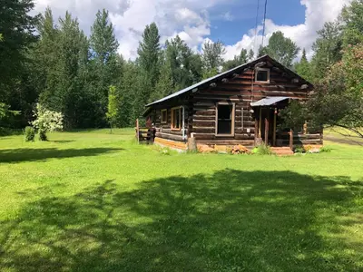 a log cabin in a field of green grass at Mini-Mooh cabin in Clearwater