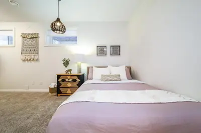 a white bedroom with a large bed and a lamp at Bali Style Home - King Bed - Fireplace - Jacuzzi - Fast Wi-Fi - Free Netflix & Garage Parking in Edmonton