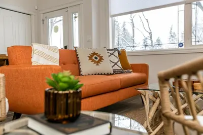 an orange couch in a living room with a window at Bali Style Home - King Bed - Fireplace - Jacuzzi - Fast Wi-Fi - Free Netflix & Garage Parking in Edmonton