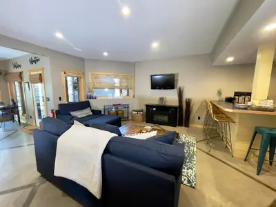 a living room with two blue couches and a kitchen at Blanchard Mountain BnB in Canmore