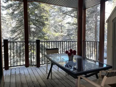 a screened in porch with a glass table on a deck at Blanchard Mountain BnB in Canmore