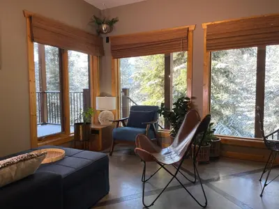 a living room with a couch and chairs and windows at Blanchard Mountain BnB in Canmore
