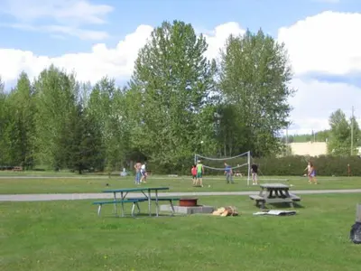 a park with picnic tables and a dog laying on the grass at Airport Inn in Quesnel