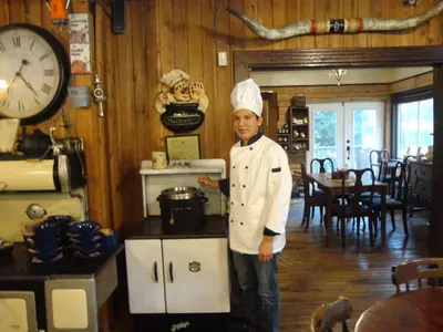a man in a chefs hat standing in a kitchen at Old Towne Inne Chuckwagon Bar & Grill in Boston Bar