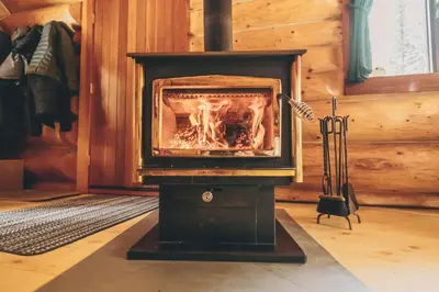 a woodburning stove in a room with a fireplace at Rocky Mountain Escape Dome & Log Cabin Rentals - Rock Lake in Rock Lake Provincial Park