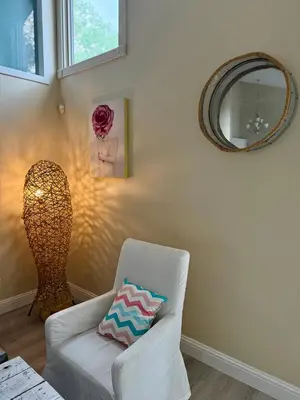 a living room with a white chair and a mirror at Banff mountain House&30 second Bus station Close C-Train& Free Parking in Calgary