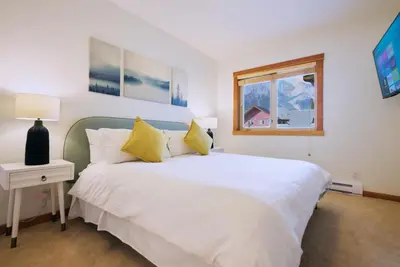 a bedroom with a white bed and a window at Mtn View Escape with King Size Bed with Outdoor Pool - Banff Pass Included! in Canmore