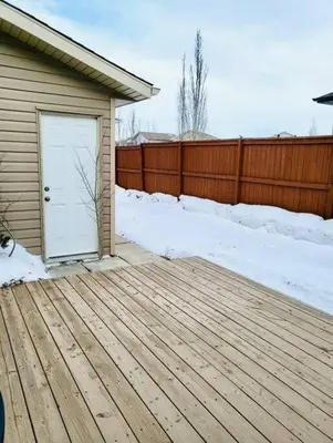 a wooden deck with a white door on a house at Spacious Basement suite in Camrose