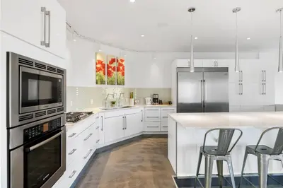 a kitchen with white cabinets and a counter with stools at Carbon Valley Ranch in Grainger