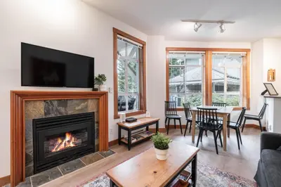 a living room with a fireplace and a table with chairs at Granite Court by Outpost Whistler in Whistler