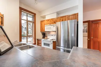 a kitchen with a stainless steel refrigerator and a sink at Granite Court by Outpost Whistler in Whistler