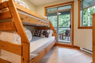 a bedroom with two bunk beds and a balcony at Granite Court by Outpost Whistler in Whistler