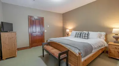a bedroom with a bed with a chair and a tv at Mountain Time - Spacious w Private Hot Tub and an Amazing View in Big White