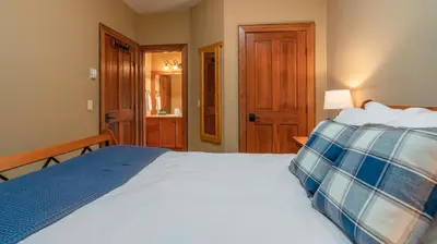 a bedroom with a white bed with a blue pillow at Mountain Time - Spacious w Private Hot Tub and an Amazing View in Big White