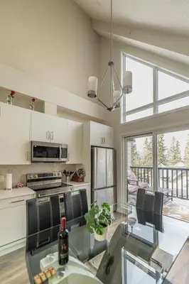 a kitchen with a glass table and black chairs at Skyline Soak - Pool & Hot Tub & Mountain Views in Canmore